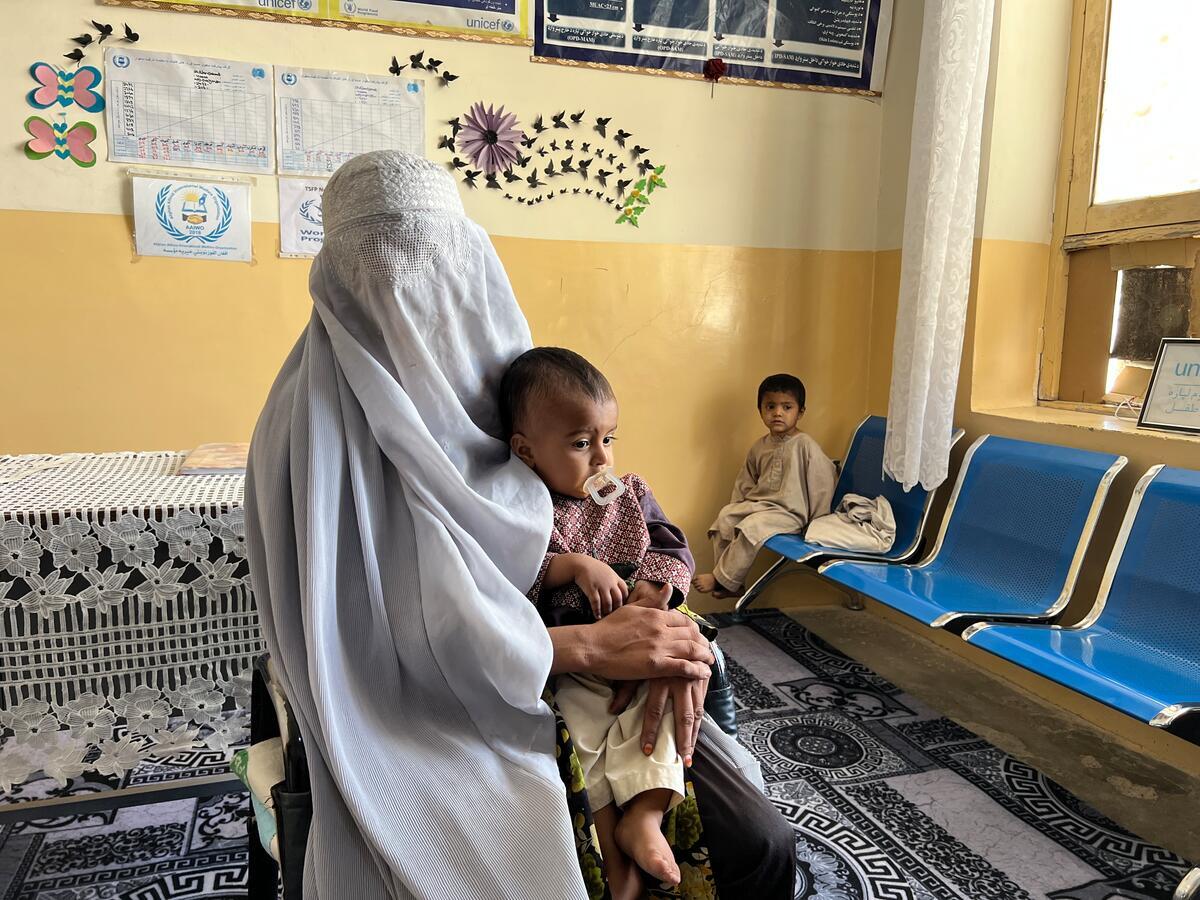 Afghanistan. Farida, eine Mutter mit zwei unterernährten Kindern, kommt in eine vom WFP unterstützte Klinik in Kandahar, um Nahrungsmittelhilfe zu erhalten.